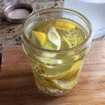 Jar filled with lemon peels and liquid, on a wooden surface.