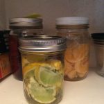 Jars of preserved citrus fruits on a shelf.
