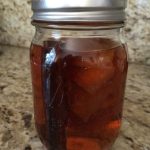 A mason jar filled with a dark liquid and some floating objects, placed on a granite countertop.