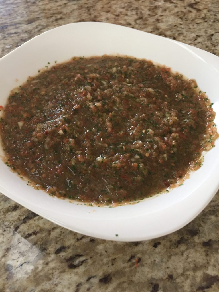 A bowl of blended salsa on a granite countertop.