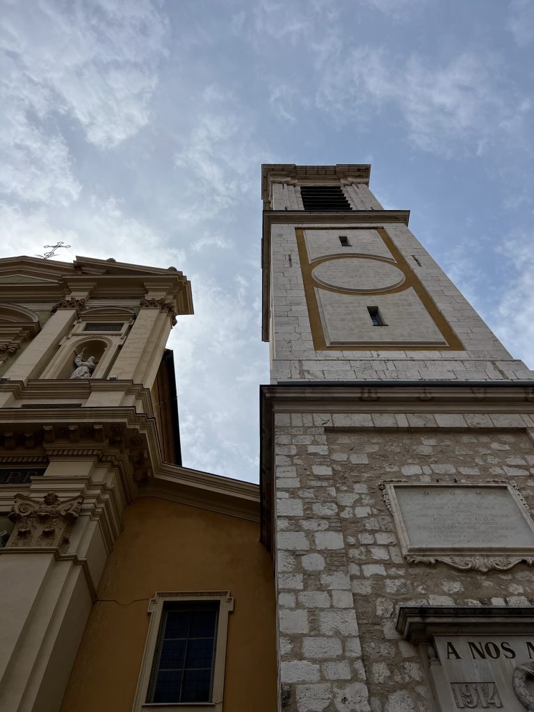 A low-angle view of a historic church facade and bell tower against a cloudy sky.