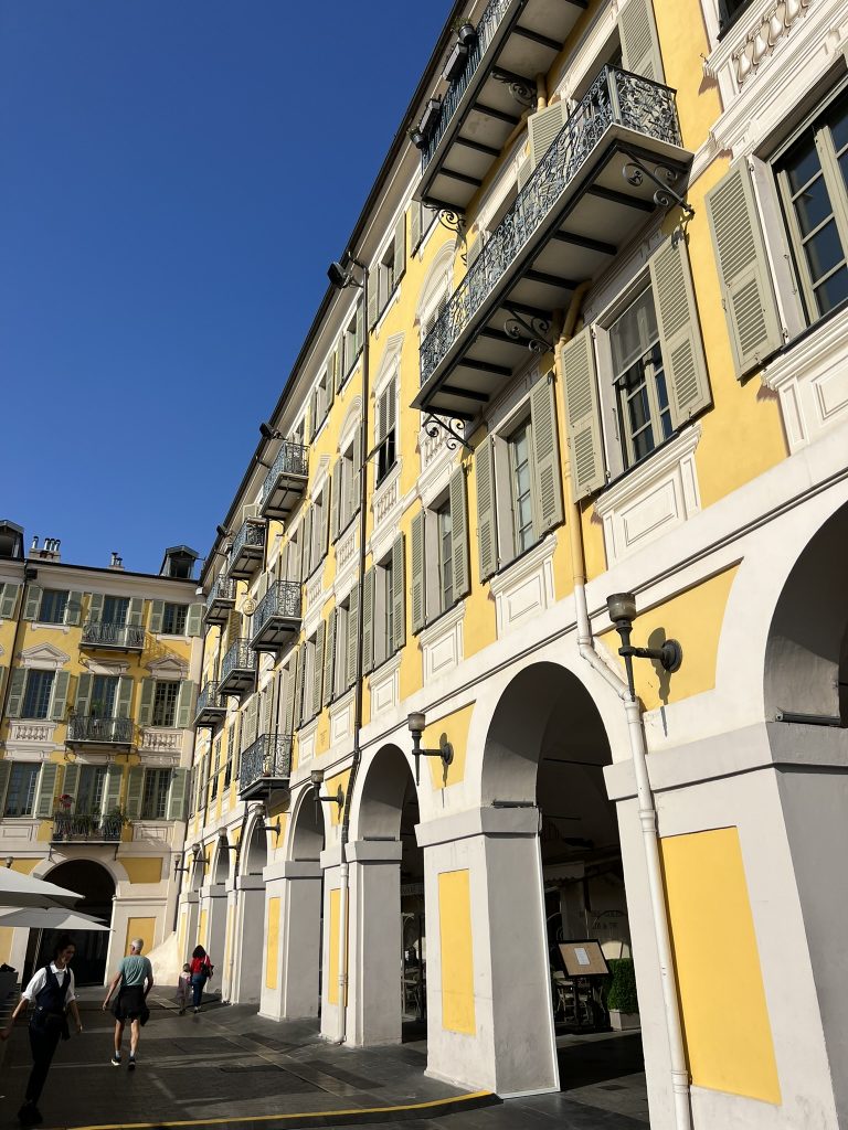 Yellow building with arched walkways and wrought iron balconies under a clear blue sky.
