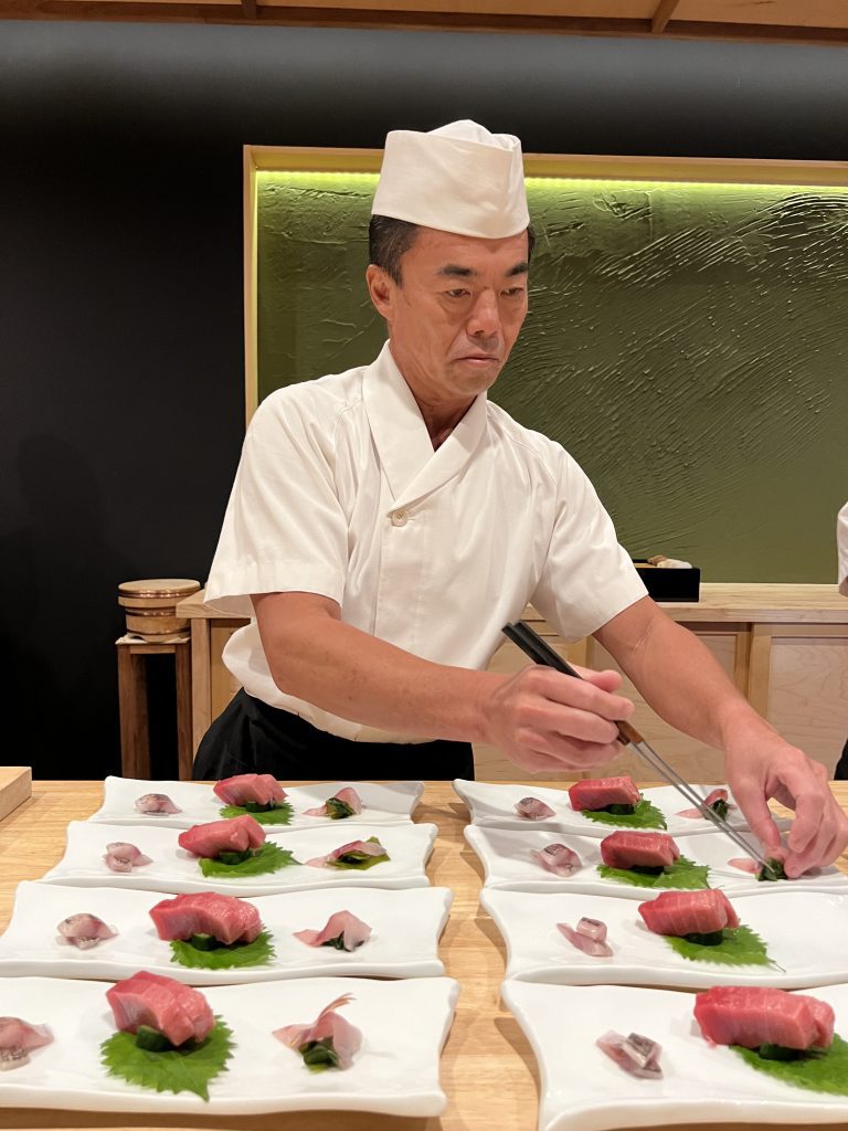 Chef preparing sushi on decorative plates.