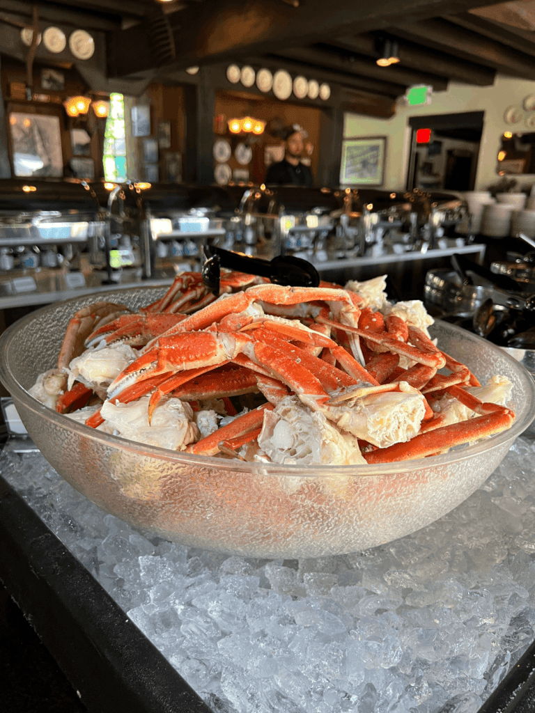 A bowl filled with crab legs on ice at a buffet.