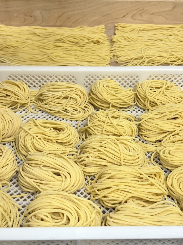 Freshly made noodles arranged in coils on a drying rack.
