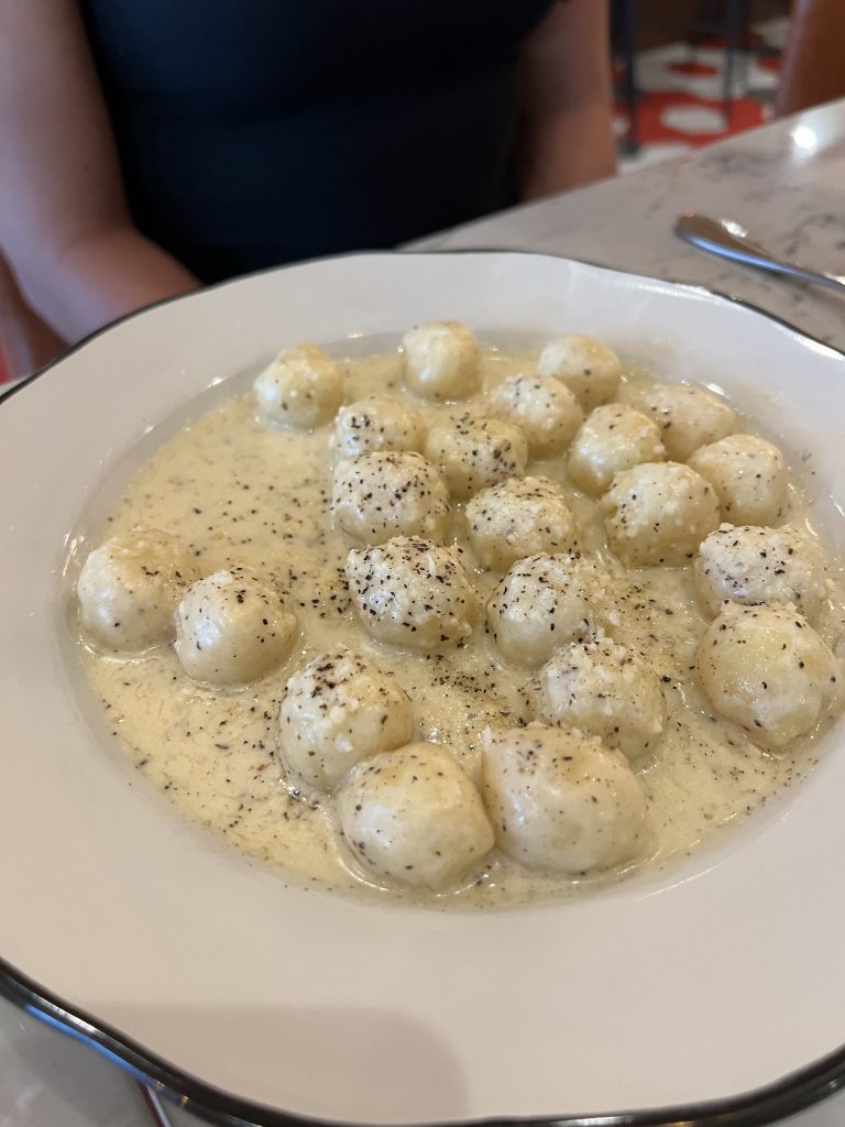 A plate of gnocchi in a creamy sauce topped with black pepper.