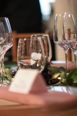 A table setting with wine glasses, a name card, and decorative foliage.