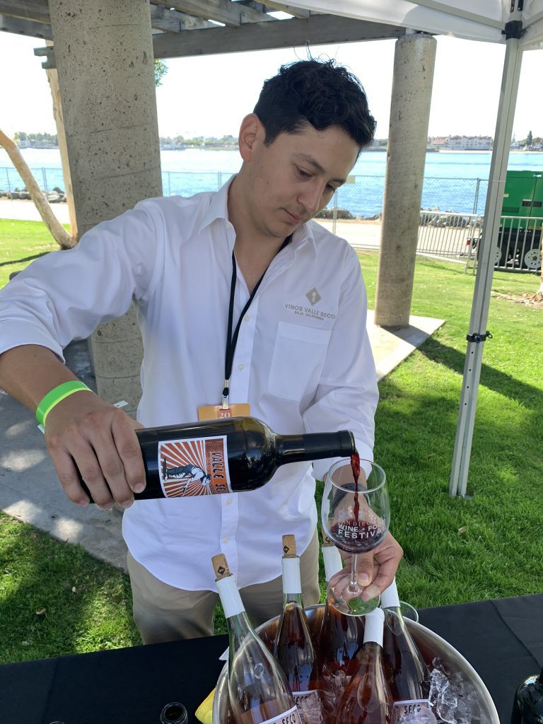 A person pouring wine into a glass at an outdoor event.